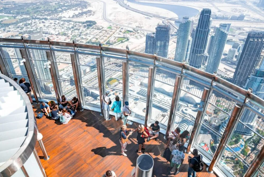 Visitors at the Burj Khalifa observation deck glass railing overlooking Dubai
