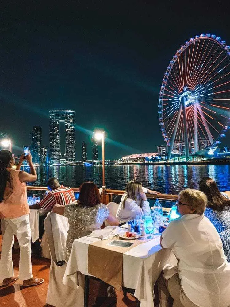 Guests dining on deck with a lit-up Ain Dubai wheel in the background